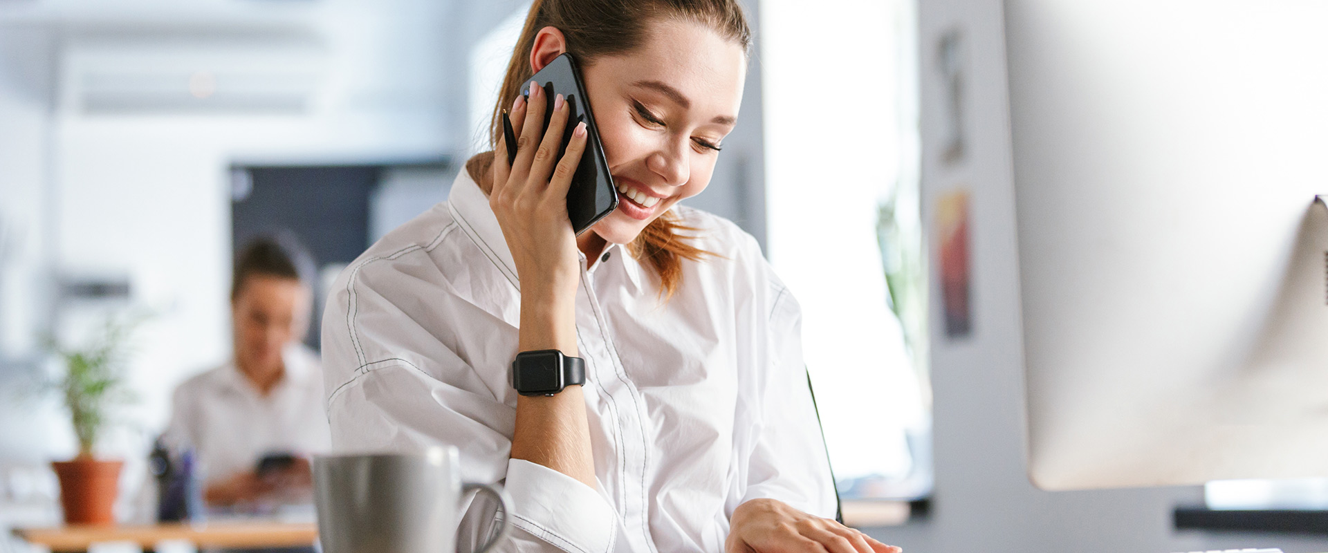 Cheerful young businesswoman sitting at her workplace